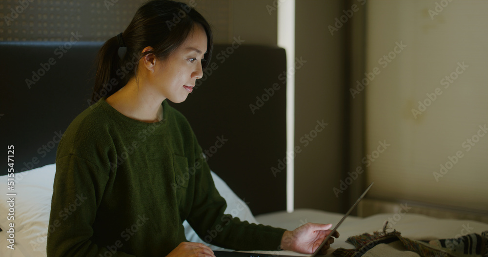 Woman work on laptop computer on bed at night Woman work on laptop computer on bed at night
