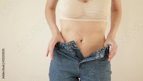 A young woman mother unbuttons her jeans and shows her scar from a cesarean section. Body positivity. diversity. Light warm natural tones. Lifestyle. High quality FullHD footage photo