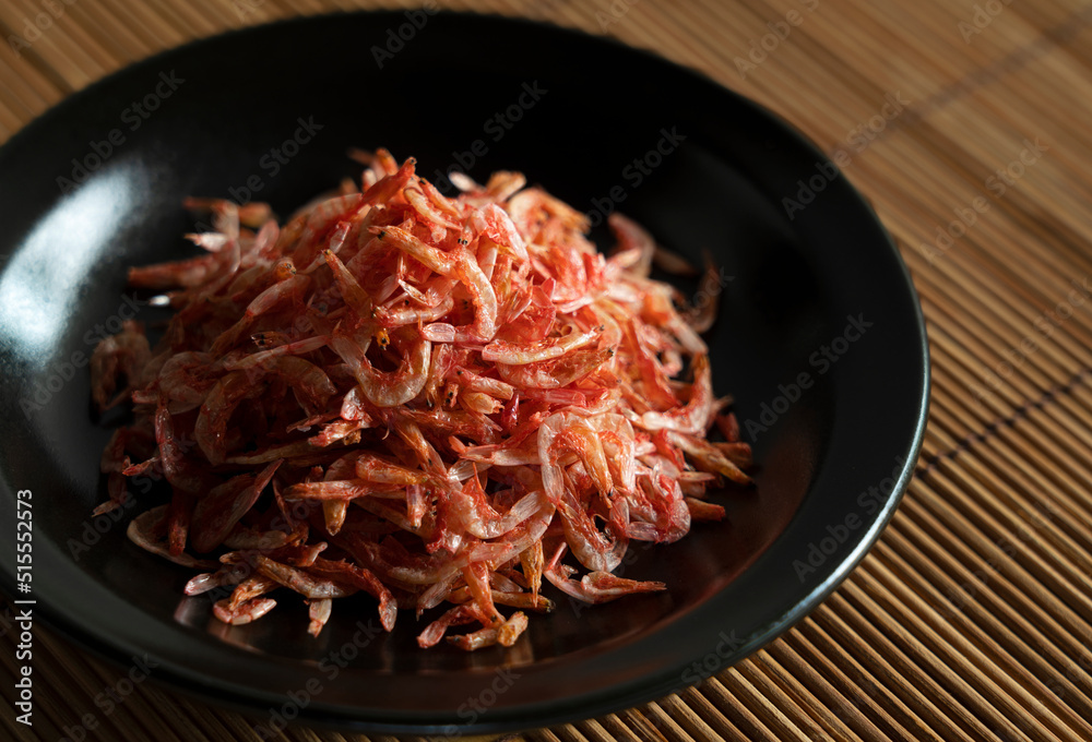 Dried sakura shrimps on a plate placed on a bamboo luncheon mat. Dried sakura shrimps on a plate placed on a bamboo luncheon mat.