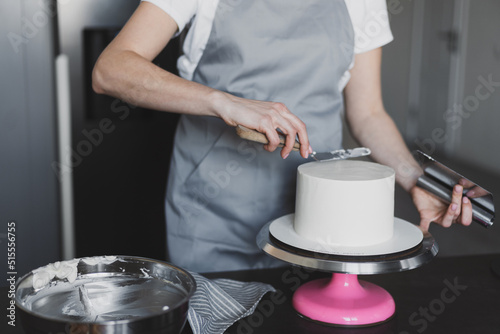 Young lovely woman pastry chef preparing a festive cake at home in the kitchen