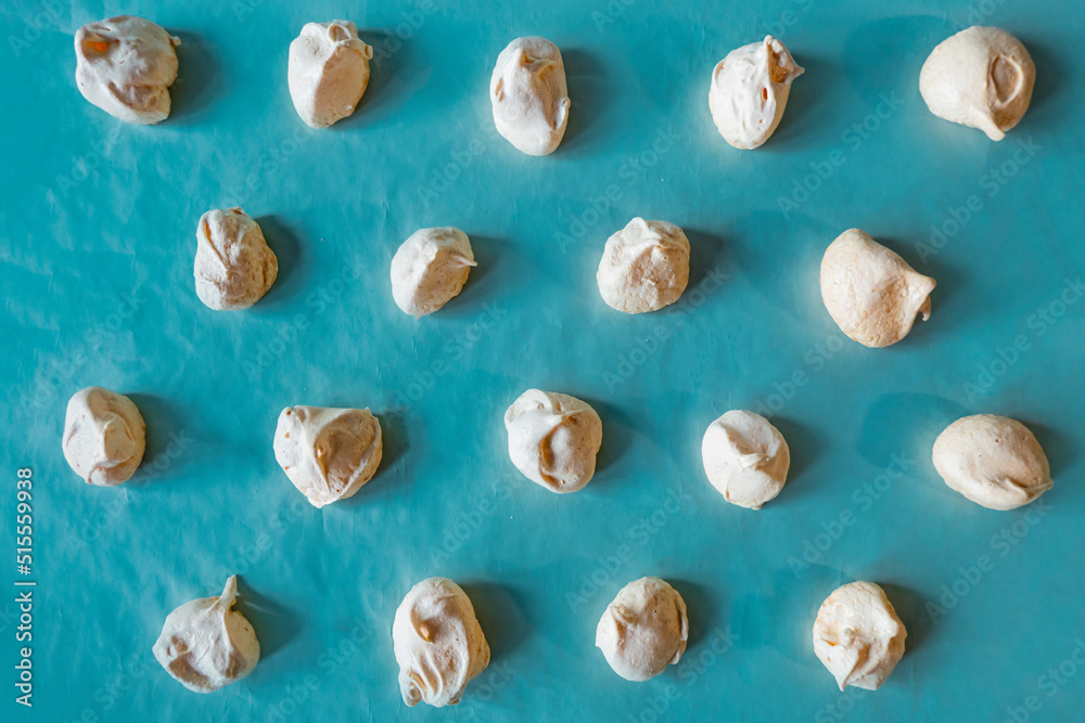 Homemade french milk-colored meringues on blue paper Homemade french milk-colored meringues on blue paper