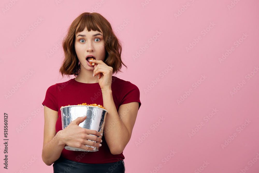 Excited shocked cute redhead lady in red t-shirt with popcorn ready for movie evening posing isolated on over pink studio background. Copy space Banner. Fashion Cinema concept. Entertainment offer Excited shocked cute redhead lady in red t-shirt with popcorn ready for movie evening posing isolated on over pink studio background. Copy space Banner. Fashion Cinema concept. Entertainment offer
