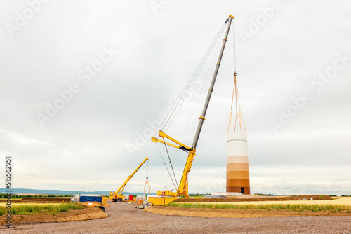 Building and assembling a construction wind turbine by crane. Farmland with construction work at the windfarm in Wörrstadt, Germany. Energy saving concept from wind turbine construction with cloud sky