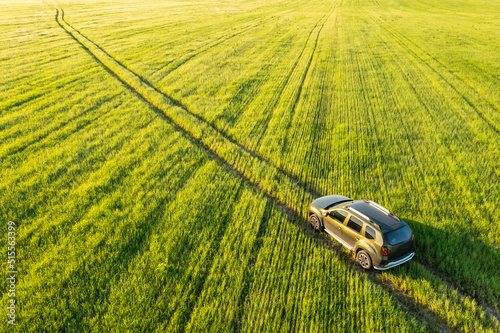 Obraz na płótnie Aerial view of Renault Duster car SUV driving on countryside road in spring field rural landscape. Car driving on corn maize plantation. w salonie