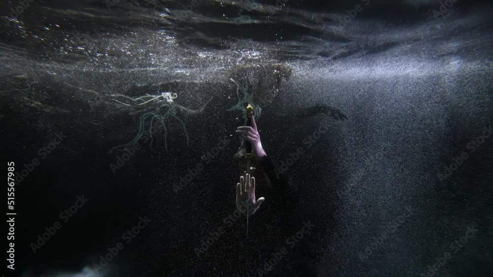 the long-haired man bowed before the sword. a woman with pearl beads hovers behind him in the dark water with bubbles
