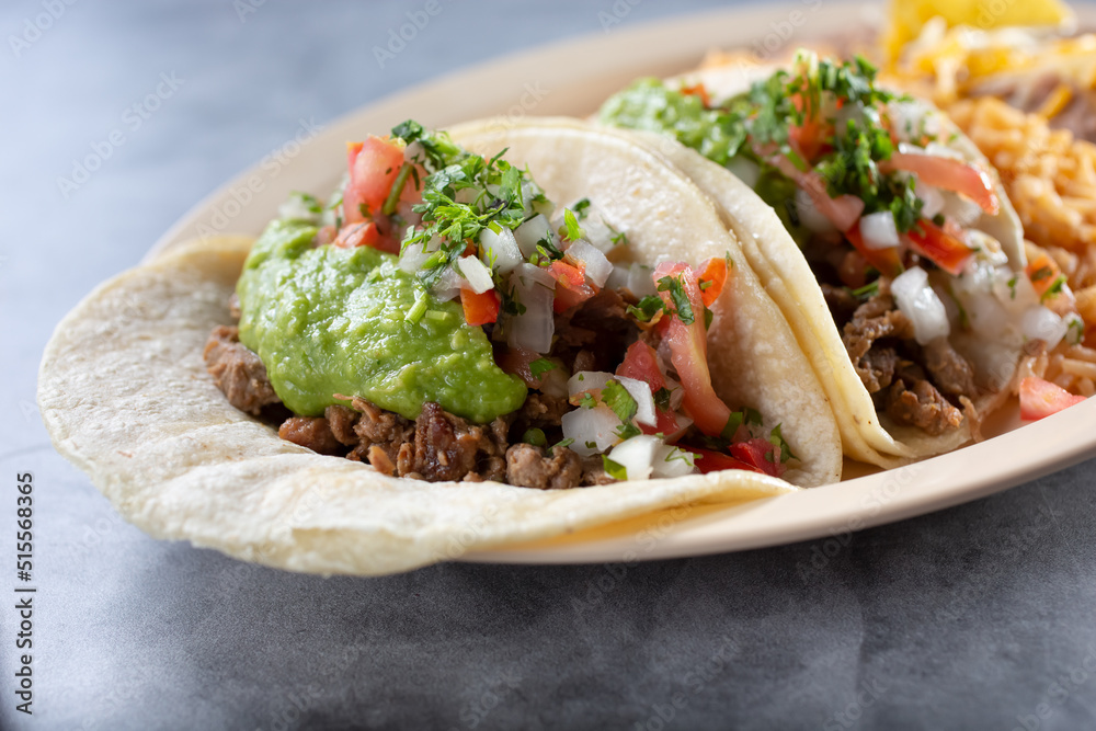 A view of a two carne asada tacos on a plate. A view of a two carne asada tacos on a plate.