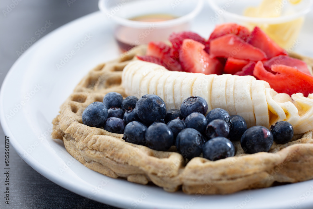 A view of a gluten-free waffles topped with assorted fruit. A view of a gluten-free waffles topped with assorted fruit.