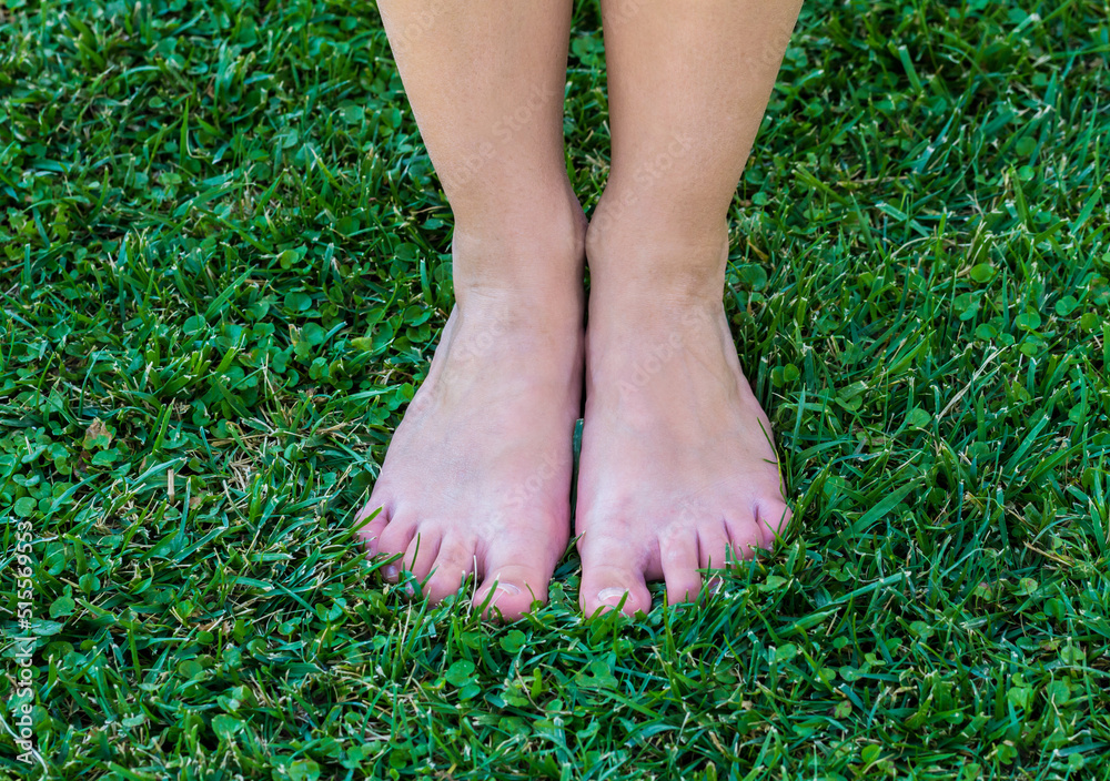 Bare feet stand on green grass.