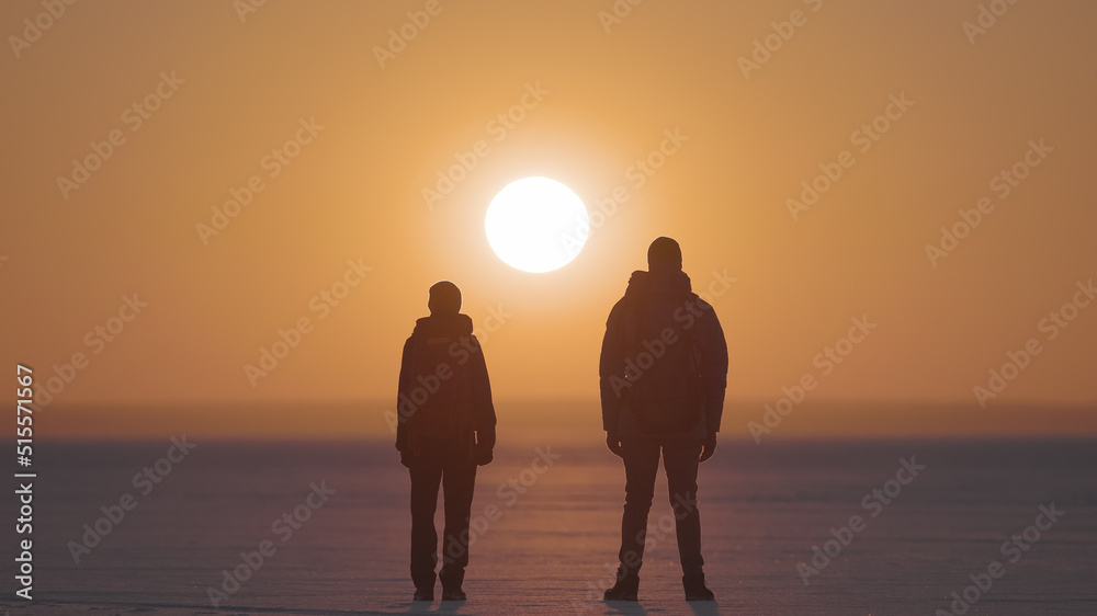 The two backpackers standing on the sunset background