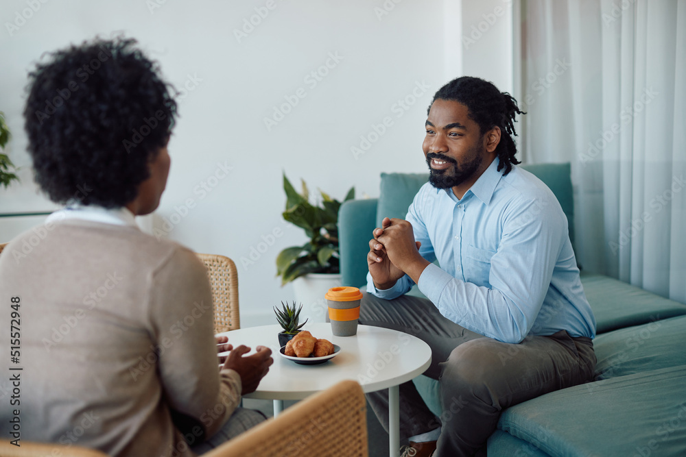 Happy black businessman talks to female colleague on coffee break in office. Happy black businessman talks to female colleague on coffee break in office.