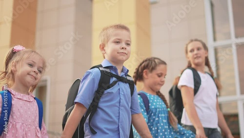 back to school. a group of schoolchildren with backpacks walk next to the school. education lifestyle kids concept. schoolboy and schoolgirl going to school. a group of children walking