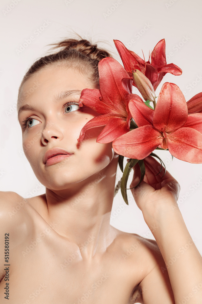 Blossom. Close-up portrait of beautiful young girl with flower isolated over white studio background. Cosmetics, natural beauty and aesthetic cosmetology concept. Blossom. Close-up portrait of beautiful young girl with flower isolated over white studio background. Cosmetics, natural beauty and aesthetic cosmetology concept.