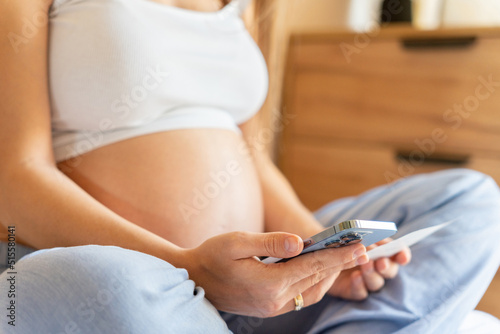 Pregnancy calendar app. Mobile pregnancy online maternity application. Pregnant mother using phone. Concept of pregnancy, maternity, expectation for baby birth.