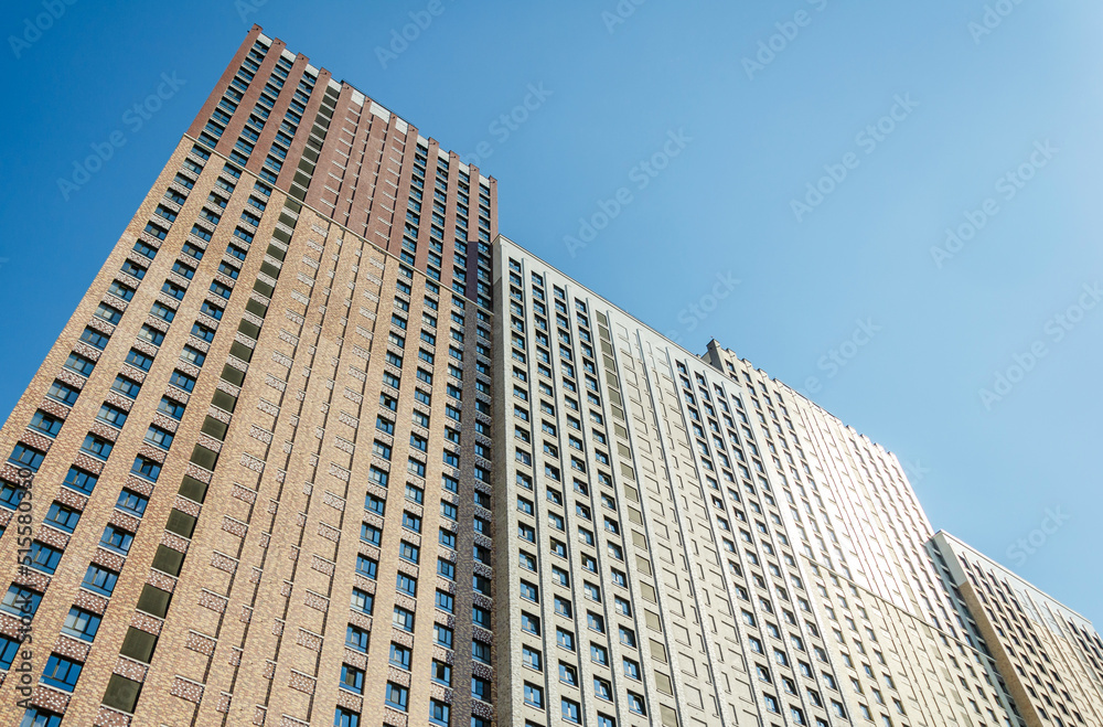 multistory modern brick residential building against the blue sky. Text space, template for advertising. Construction concept, mortgage, home insurance, affordable housing