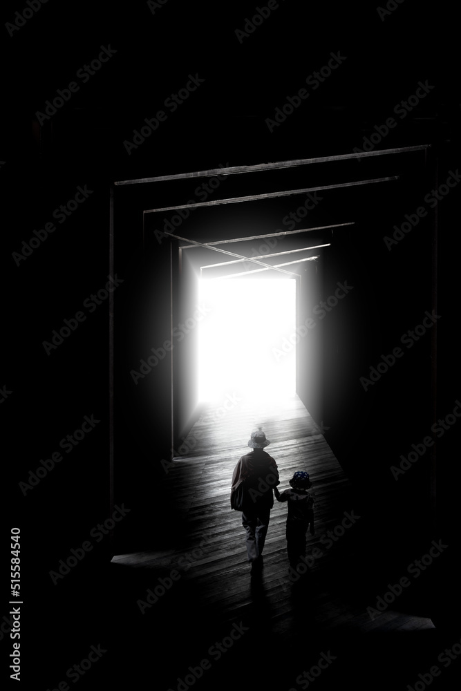 Profile of mother and daughter walking into the light. Creepy hallway with the little girl. Dark otherworldly personality. Light in a dark long corridor. The Ghost of a little girl in the house.