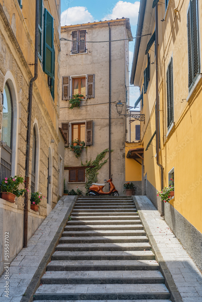 View of Carrara (Tuscany): glimpse of a typical italian alley with a marble staircase and flowers hanging from the balconies