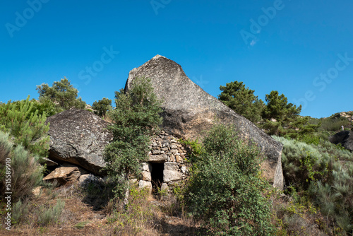 Porta de entrada de uma casa em baixo de uma enorme pedra a meio do monte. Casa antiga em ruínas construida entre rochas enormes
 photo