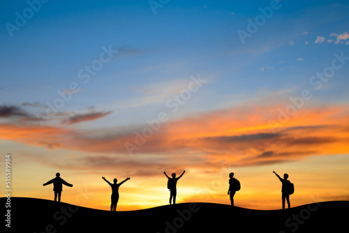 Silhouette small group of young traveler and backpacker standing and open arms on top of the mountain with twilight sky. They are enjoyed traveling and was successful when he reached the summit.