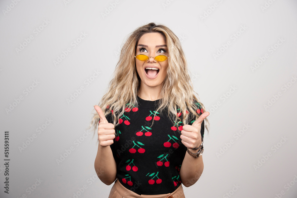 Smiling woman showing thumbs up and looking away over gray background