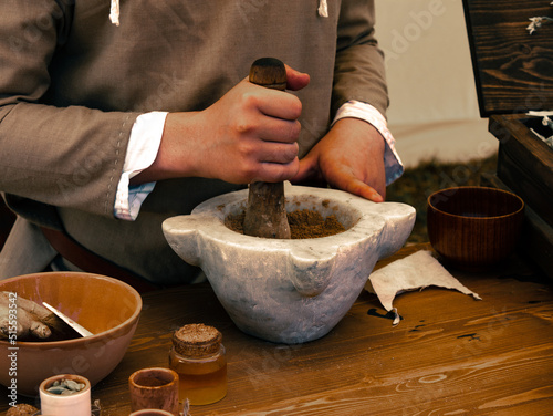herbalist table person grinds seeds with mortar and pestle