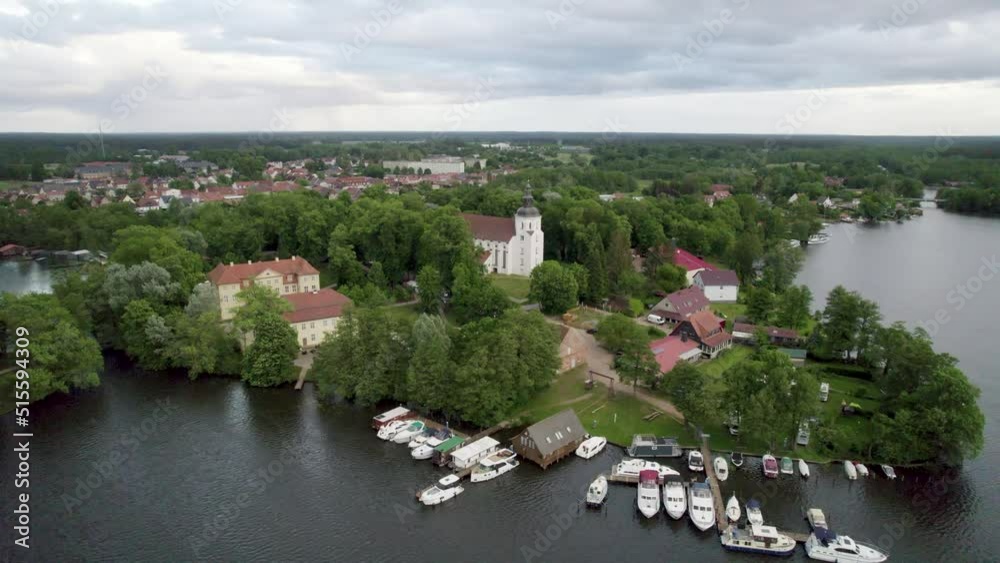 Drone flight around Johanniterkirche in Mirow. Boats at a port in a town. Drone flight around Johanniterkirche in Mirow. Boats at a port in a town.