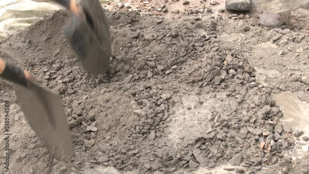 Mixing concrete energetically by hand with four shovels. Close up. Mixing concrete energetically by hand with four shovels. Close up.