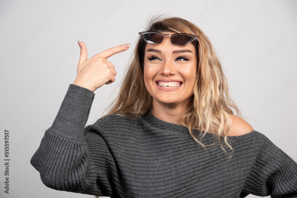 Happy woman pointing at her eyeglasses on gray background Happy woman pointing at her eyeglasses on gray background