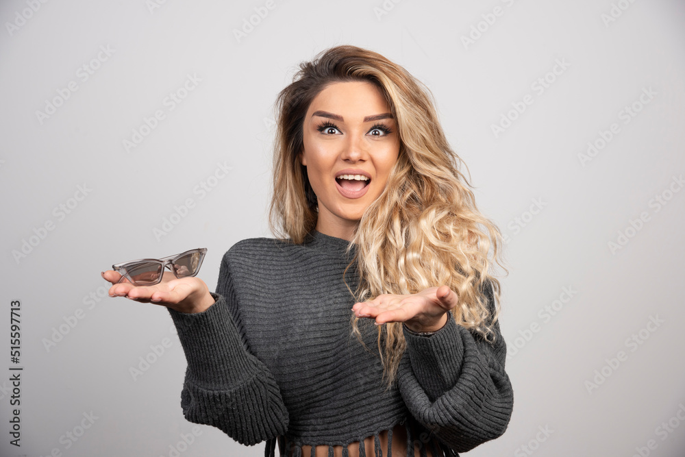 Young woman holding eyeglasses and looking at camera Young woman holding eyeglasses and looking at camera