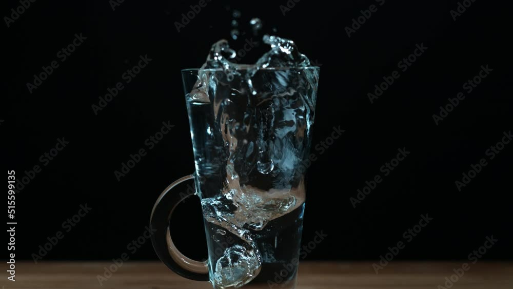 Super Slow Motion Coin Falling into Glass of Water on Table Super Slow Motion Coin Falling into Glass of Water on Table