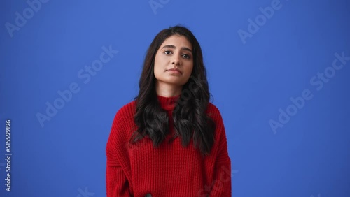 Bored Indian brunette woman sticking out her tongue isolated over blue background photo