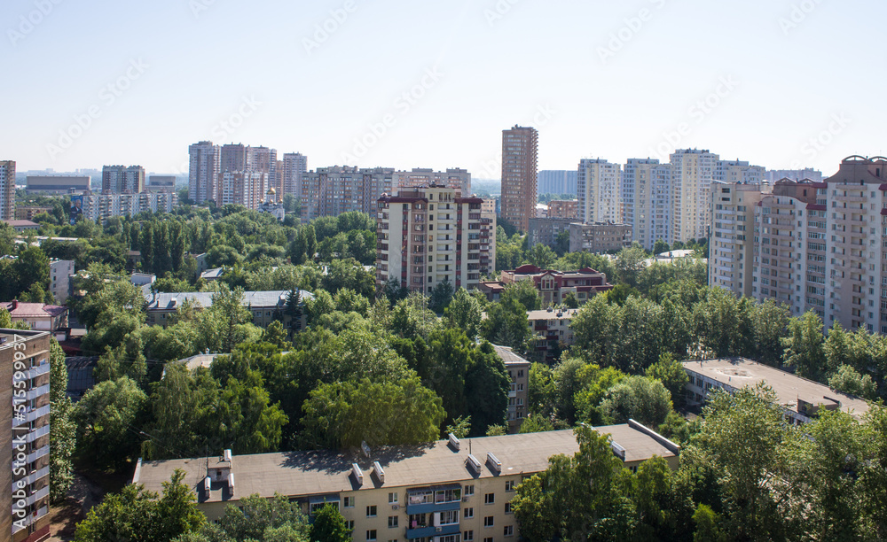 Panoramic top view - cityscape with modern buildings and lush tree foliage on a clear sunny summer day and blue sky Panoramic top view - cityscape with modern buildings and lush tree foliage on a clear sunny summer day and blue sky