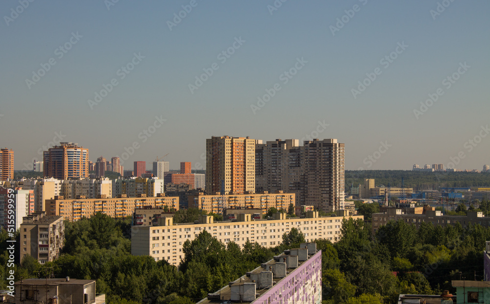 Panoramic urban landscape - modern high residential buildings among green trees on a cloudy summer day