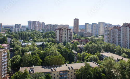 Panoramic top view - cityscape with modern buildings and lush tree foliage on a clear sunny summer day and blue sky