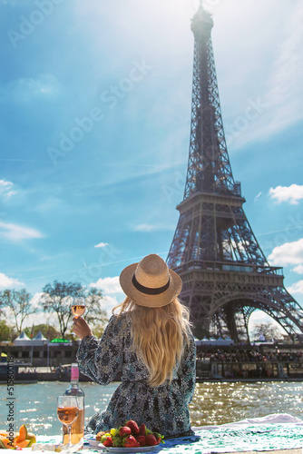A woman near the Eiffel Tower drinks wine. Selective focus. © yanadjan