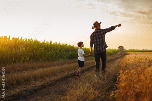 father and son holding hands walking in farmland