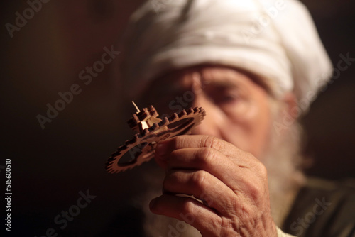 Old Islamic Scientist While Exploring a Wooden Gear