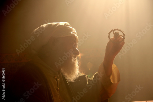 An old and historic Islamic scientist is working in his studio writing, reading and exploring.