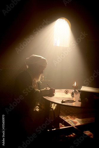 Photography An old and historic Islamic scientist is working in his studio writing, reading and exploring