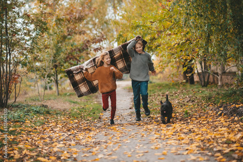 happy children run along the road. Sister and brother in autumn park with dog