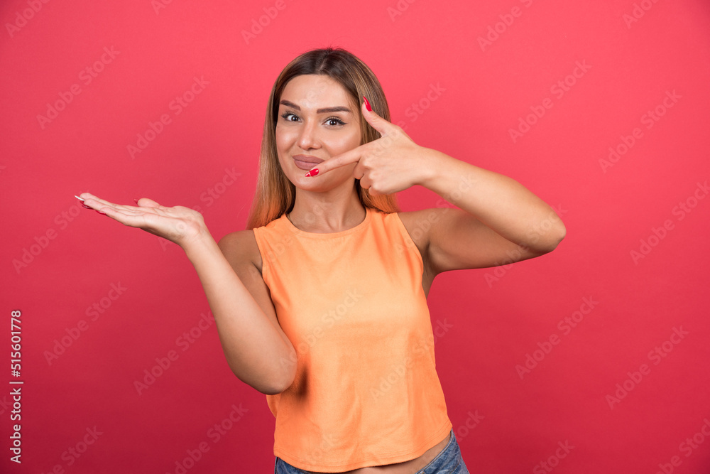 Pretty young woman pointing her hand on red background Pretty young woman pointing her hand on red background