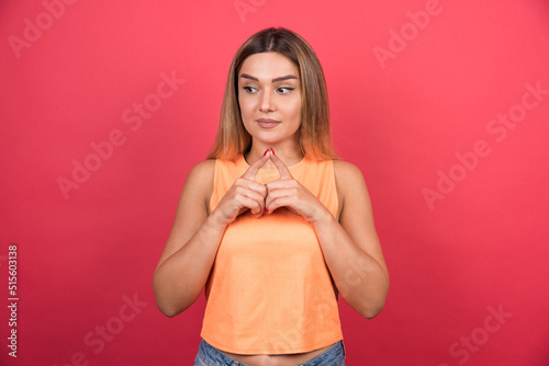 Young woman touching her fingers together on red background