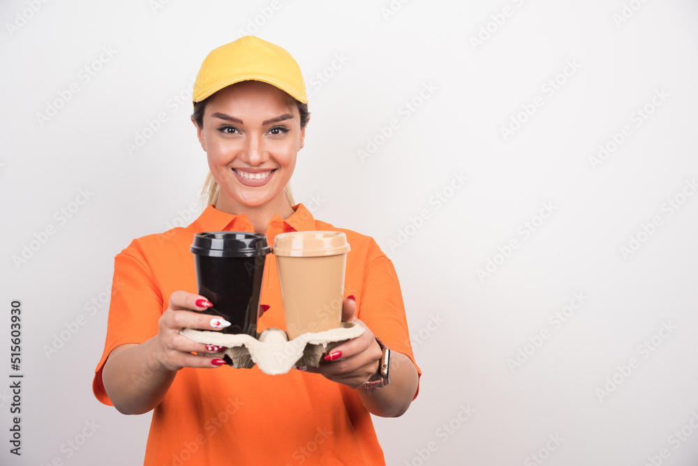 Happy woman courier holding two cups of coffees on white background