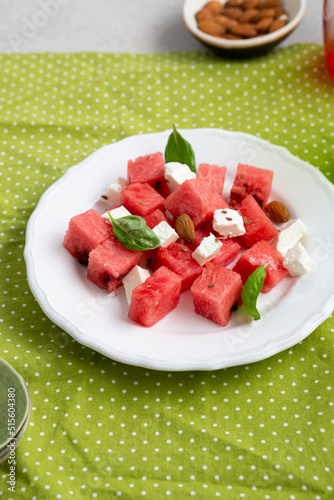 Healthy summer watermelon feta cheese salad on white plate green textile
