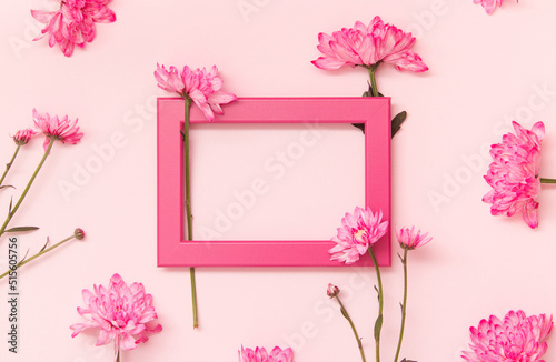 Pink frame with flowers around it on pastel background. Floral greeting card. photo