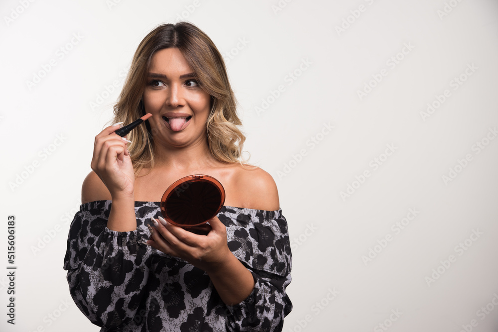 Young woman applying lipstick on white background Young woman applying lipstick on white background