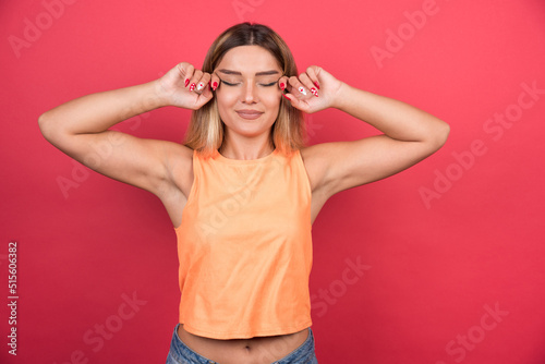 Happy young woman touching her eyes on red background