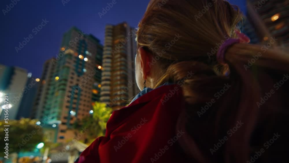 Big city view. Woman in red jacket watches big city at night. Shaky hand held camera Big city view. Woman in red jacket watches big city at night. Shaky hand held camera