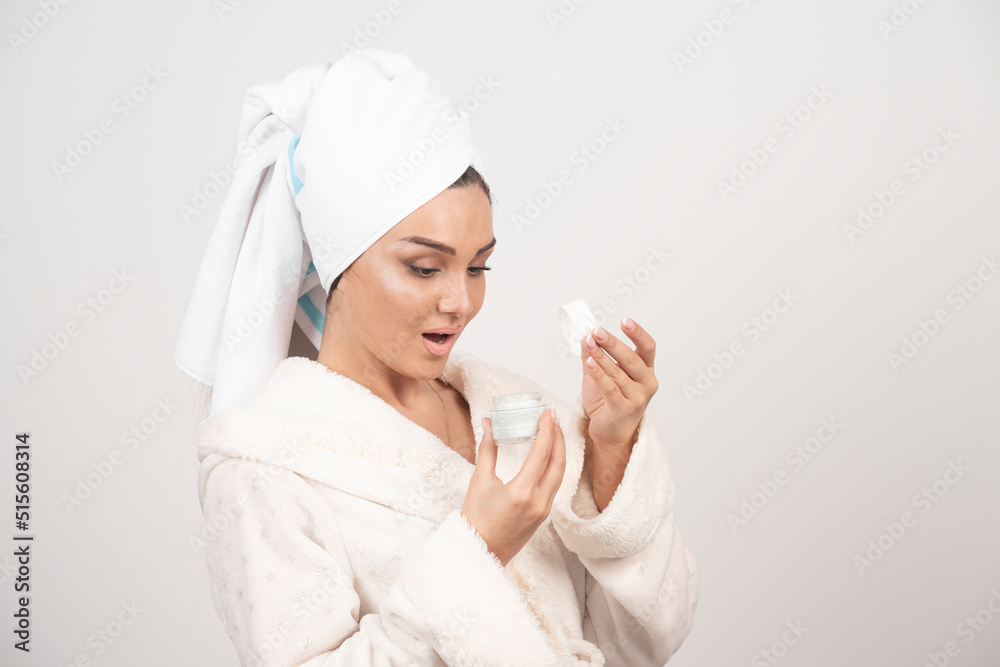 Young woman in a bathrobe applying a cream Young woman in a bathrobe applying a cream