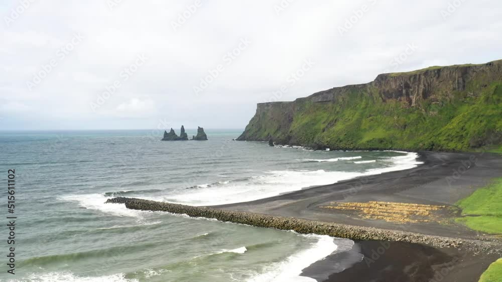 Black sand beach with large rocks, mountains and breaker in Vik, Iceland with drone video moving down. Black sand beach with large rocks, mountains and breaker in Vik, Iceland with drone video moving down.