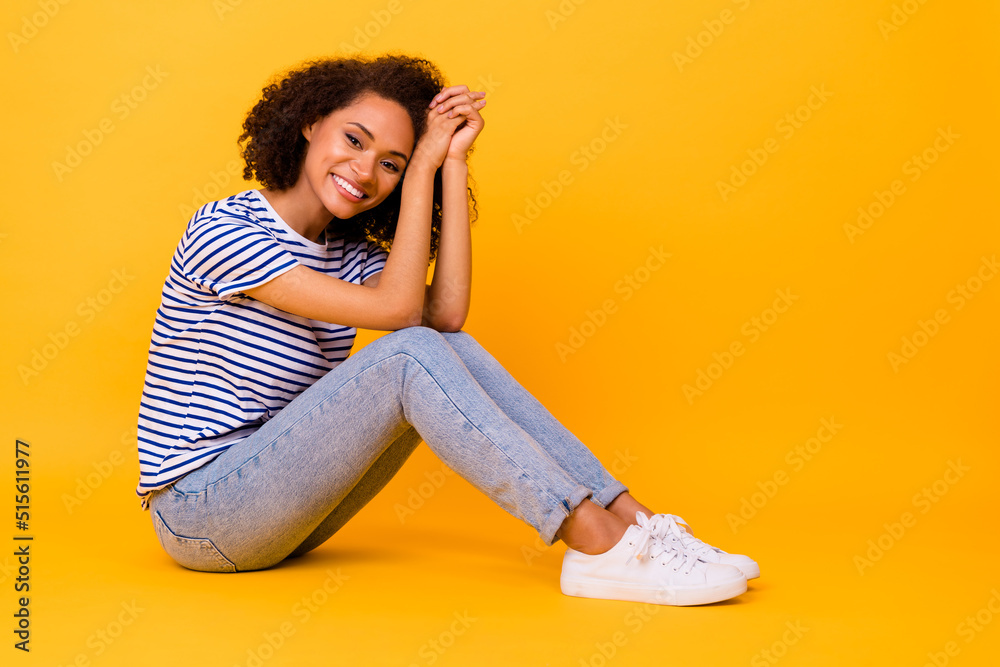 Full length profile portrait of adorable lovely lady sit floor toothy smile isolated on yellow color background Full length profile portrait of adorable lovely lady sit floor toothy smile isolated on yellow color background